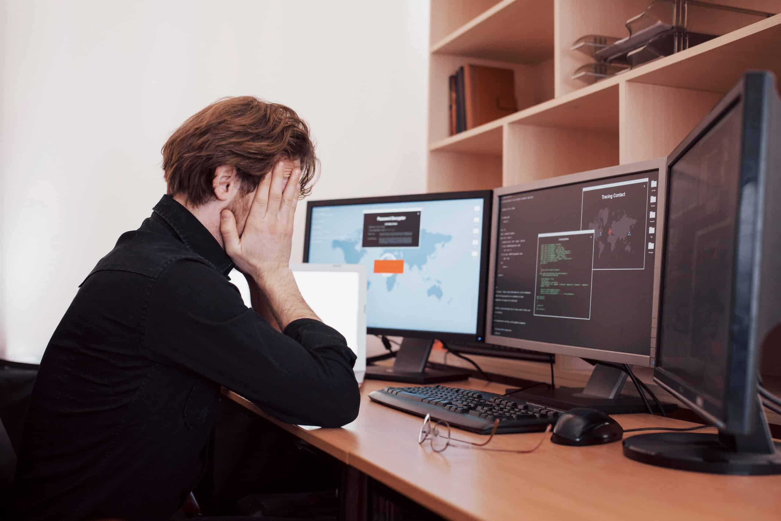 the young dangerous hacker breaks down government services by downloading sensitive data and activating viruses. a man uses a laptop computer with many monitors